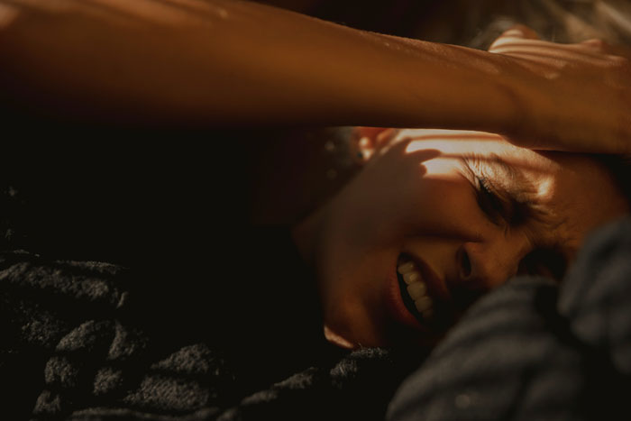 Woman waking up boyfriend in bed, showing a playful morning moment typical in normal couples' daily routine.