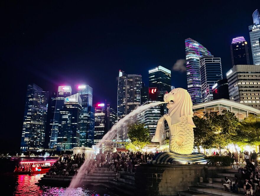 Night cityscape of Singapore with the Merlion statue and illuminated skyscrapers, showcasing cities where sleep is optional.
