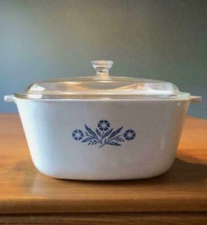 Classic nostalgic blue and white CorningWare casserole dish with glass lid on wooden surface, vintage kitchenware.