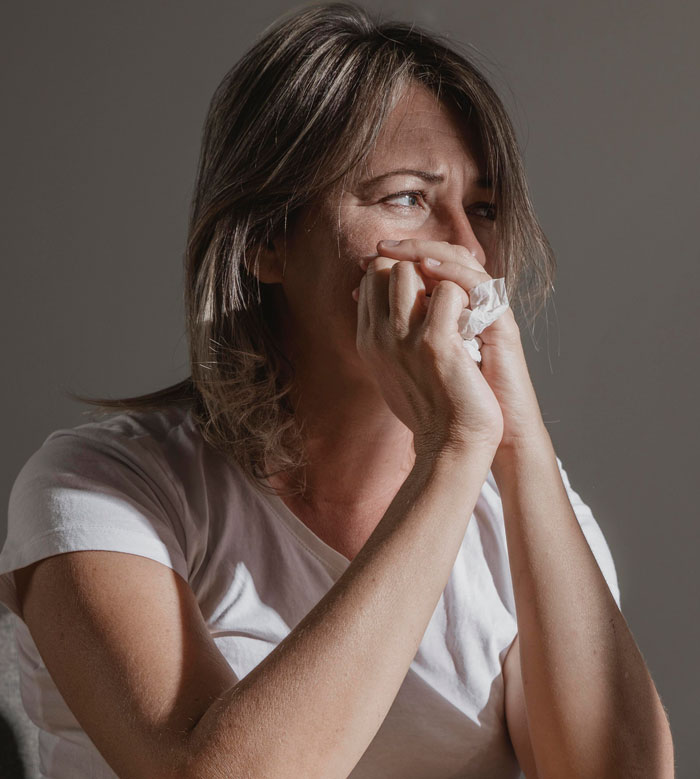 Woman holding tissue crying, emotional reaction after mother-in-law shamed her in front of everyone.