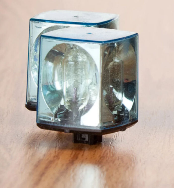 Clear plastic nostalgic night light bulb cover placed on a wooden surface reflecting light and vintage design.
