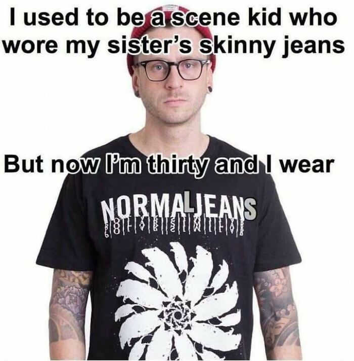 Man wearing glasses and a red beanie, with tattoos, wearing a black shirt and a meme about jeans and growing up.