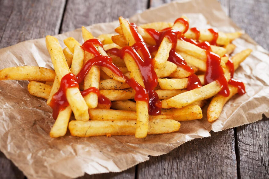 French fries with ketchup on brown paper, illustrating common pet peeves related to food habits that divide a room.