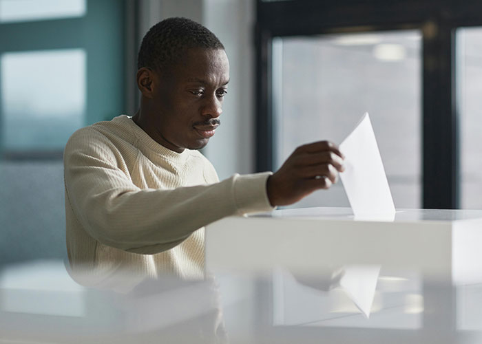 Man placing ballot in box demonstrating thoughtful participation in things countries have that just make sense concept