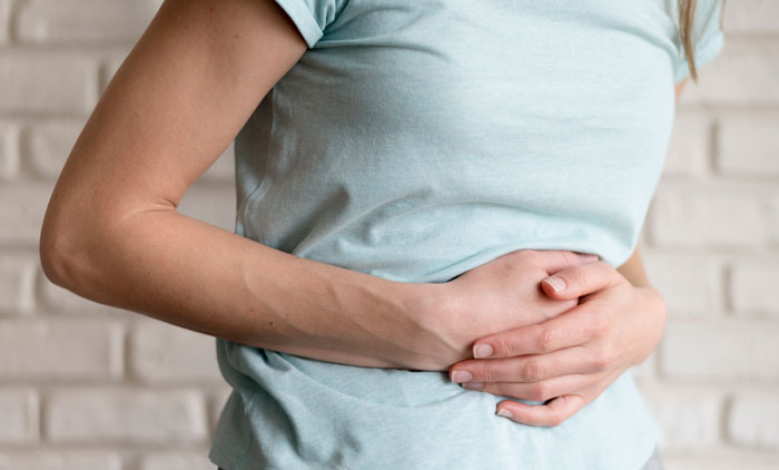 Person in a light blue shirt holding their stomach, symbolizing mysteries that have sent many people down the rabbit hole.