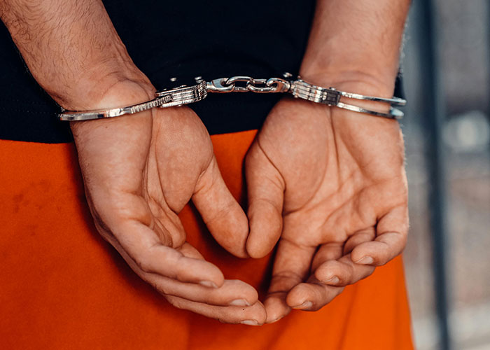 Hands in handcuffs behind a person, illustrating countries having things that just make sense to adopt worldwide.