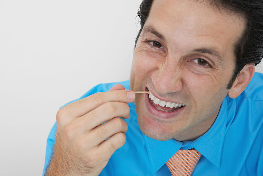 Man in blue shirt eating with his mouth open using a toothpick, illustrating common pet peeves that divide a room.