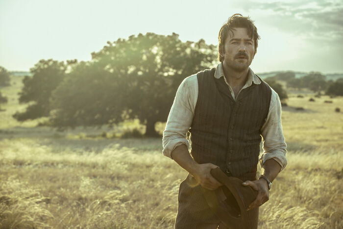 Man in vintage clothing holding a hat in a rural field, representing the Yellowstone prequel 1944 release date and plot. Man in vintage clothing holding a hat in a rural field, representing the Yellowstone prequel 1944 release date and plot.