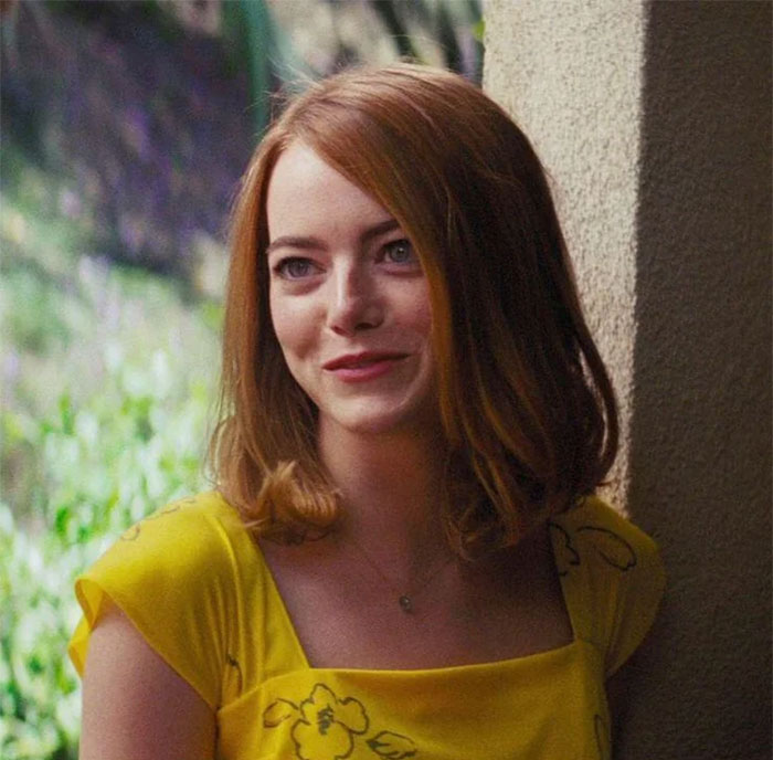 Young woman with red hair in a yellow dress, representing women going undercover in incel forums for investigation.