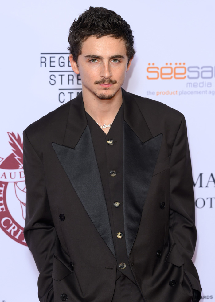 Timoth&eacute;e Chalamet at event in a black suit, sparking conspiracy theories after hotel appearance with Anamaria Vartolomei.