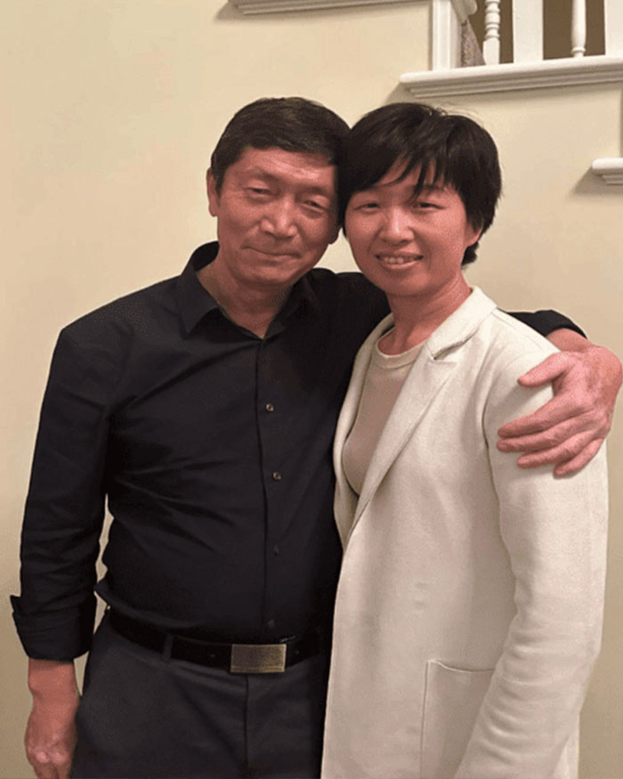 Couple posing indoors with arm around each other in a casual setting, related to surrogate suing couple with 21 kids.