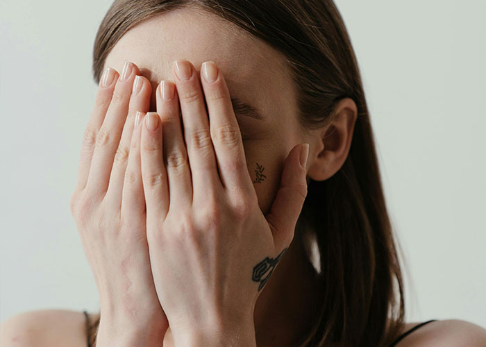 Young woman covering her face with hands, expressing emotion in relatable today I messed up stories context.