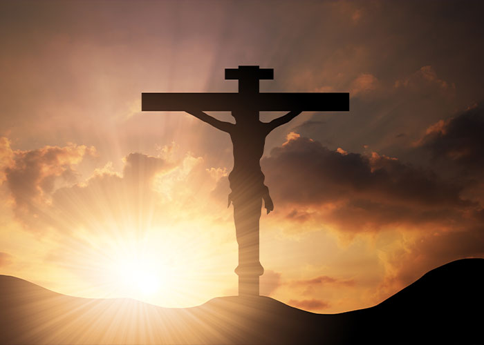 Silhouette of Jesus on the cross during sunset with dramatic clouds, symbolizing Elon Musk's controversial comment theories.