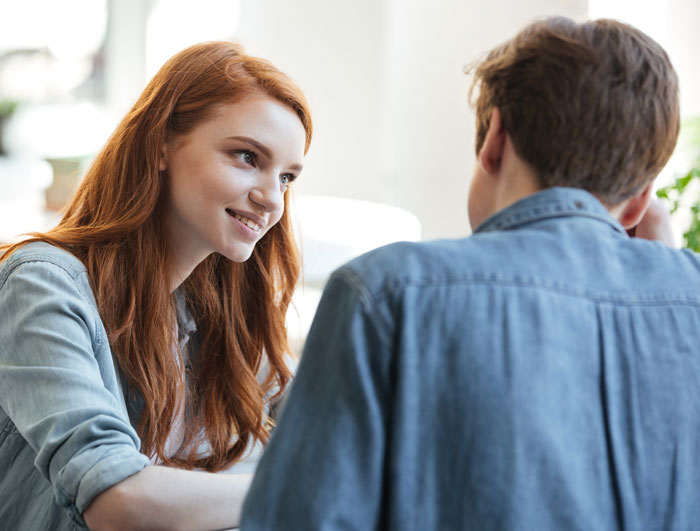 Woman with red hair talking to a man, symbolizing a woman realizing her late brother's baby isn&rsquo;t his after testing suspicions.