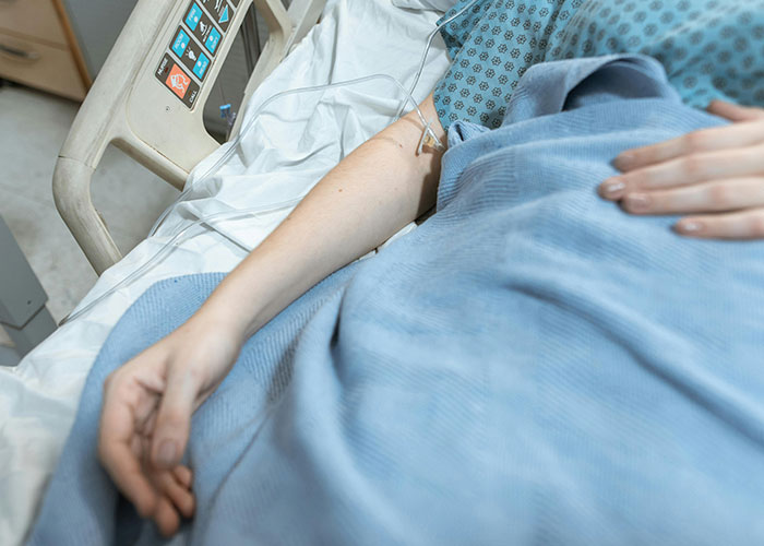 Patient in hospital bed with IV, highlighting emotional tension in teen and stepmom relationship on wedding day.