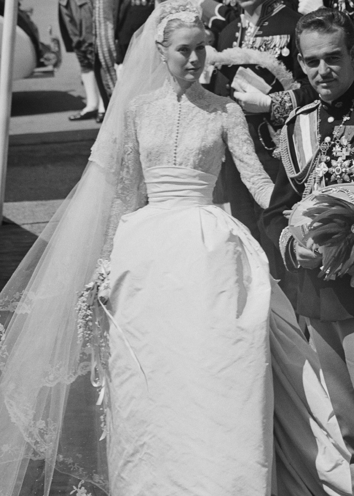 Black and white photo of a royal wedding dress with lace details and a long veil, highlighting royal wedding dresses buzz.