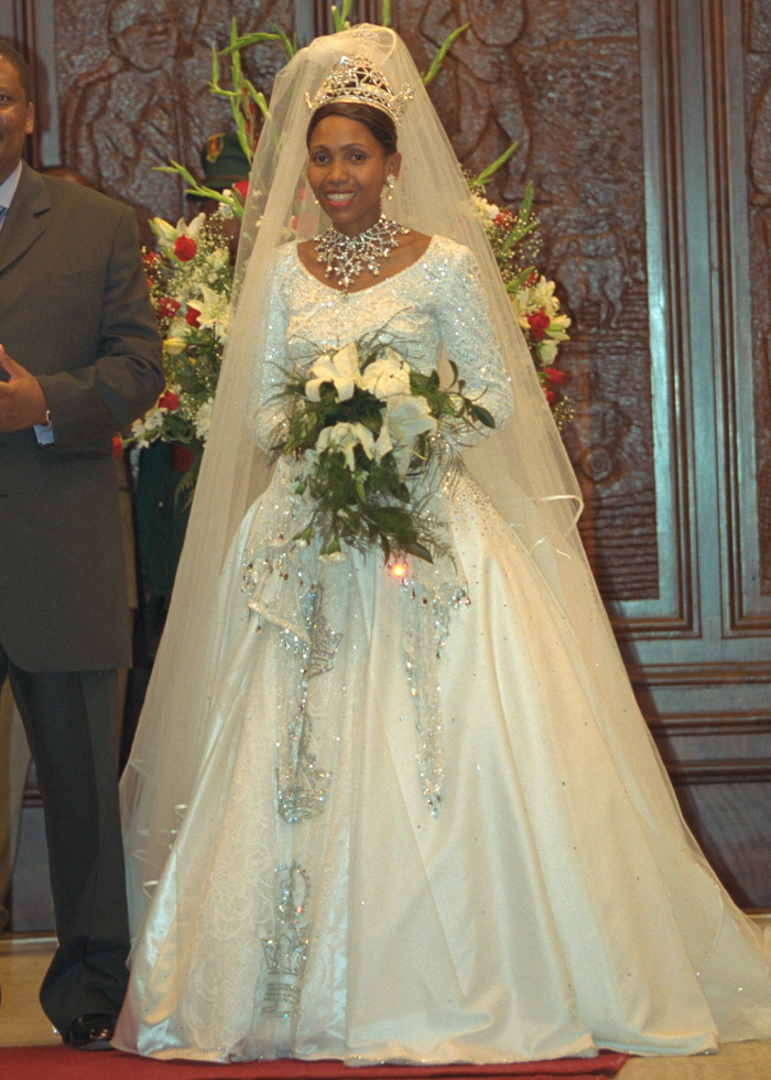 Bride in a sparkling royal wedding dress with a jeweled tiara, holding a bouquet, sparking buzz in royal wedding fashion.