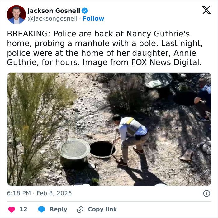 Police officer probes manhole near Nancy Guthrie's home during investigation into her disappearance in a dry, scrubland area.