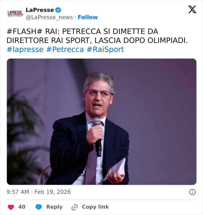 Man in suit and glasses speaking into microphone during event, linked to Winter Olympics host forced to resign controversy.