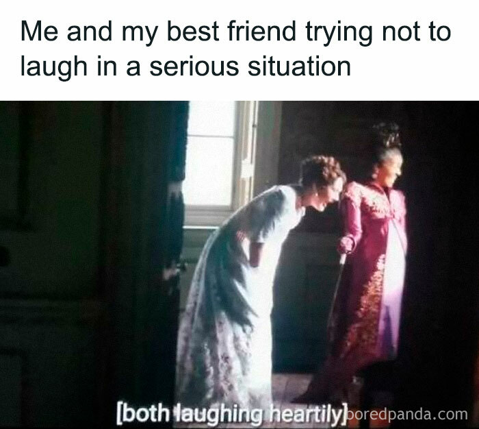 Two women in period costumes laughing quietly in a dim room, capturing a Bridgerton meme moment about serious situations.