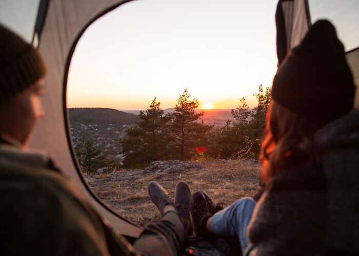Two people watching a sunrise from inside a tent, symbolizing brutal wake-up calls that led to immediate change.