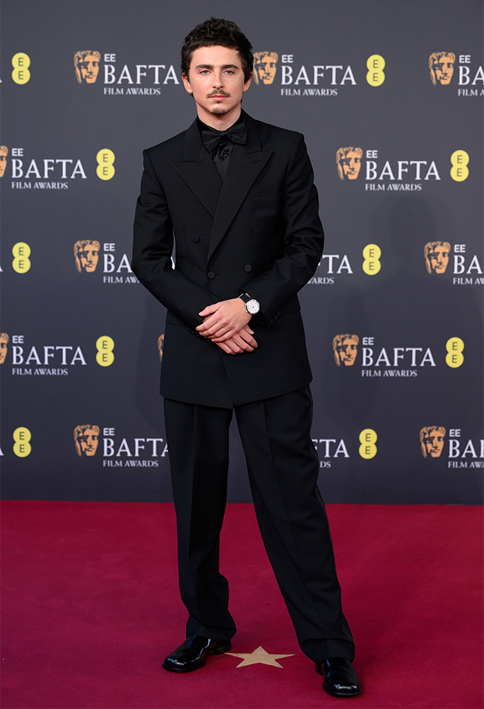 Man in a black tuxedo posing on the red carpet at the BAFTA 2026 event showcasing stylish red carpet outfits.