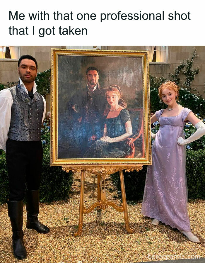 Two Bridgerton characters posing beside a framed painted portrait dressed in Regency-era outfits in an elegant garden setting.
