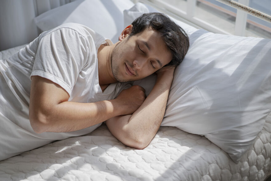 Man peacefully sleeping on a bed in sunlight, illustrating common pet peeves that instantly divide a room.