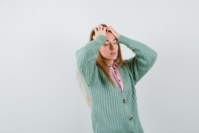 Young woman with eyes closed and hands on head, expressing fear from chilling sounds signaling immediate disaster