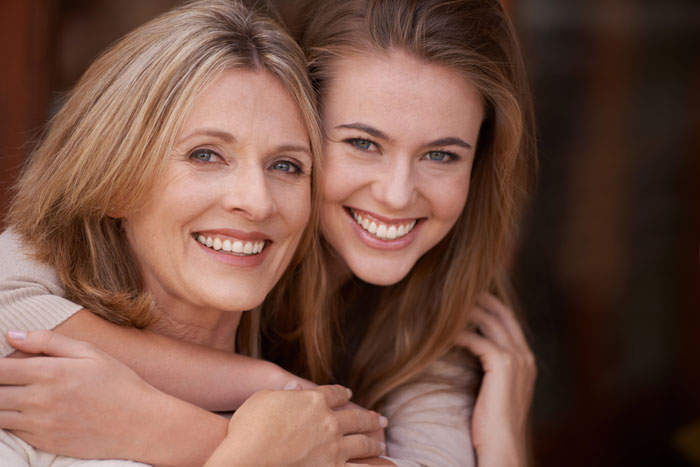 Smiling mother and daughter hugging closely, showing a warm family bond and playful connection between them.
