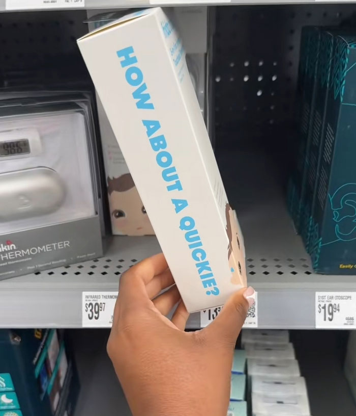 Hand holding a Frida Mom product box with the text How About A Quickie in a store aisle with medical devices.