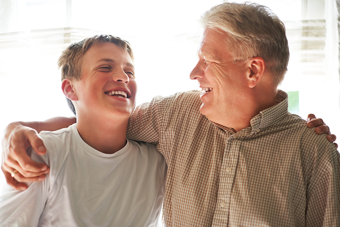 Middle-aged man and teenage boy smiling and embracing, illustrating family dynamics with boyfriend’s son at home.