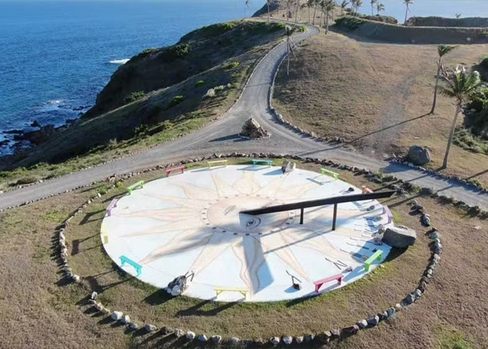 Large sundial on a coastal hill with a nearby road and ocean view linked to mobile game players catching Pok&eacute;mon on Epstein Island.