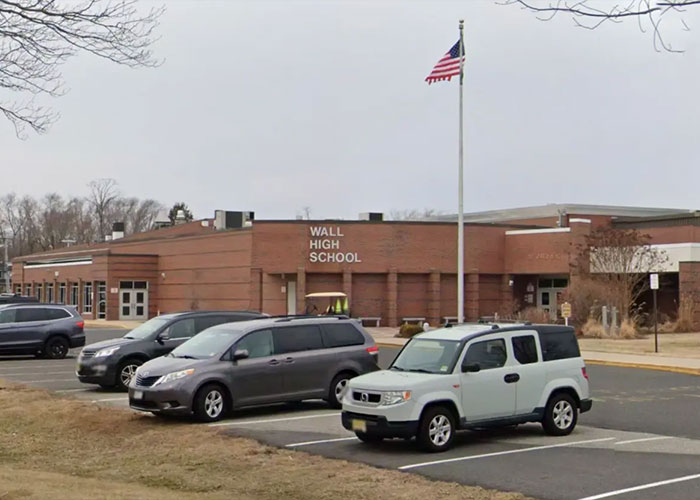 Wall High School exterior with parked cars and an American flag, related to judge firing back at teacher incident.