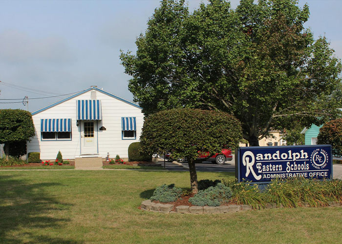 Randolph Eastern Schools administrative office building with trees and lawn in bright daylight.