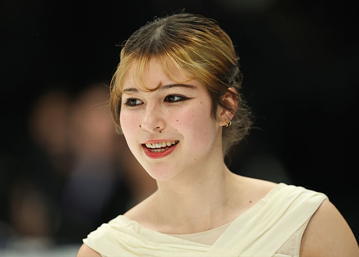 Young woman smiling with winged eyeliner and light hair, highlighting viral look health experts warn fans against copying.