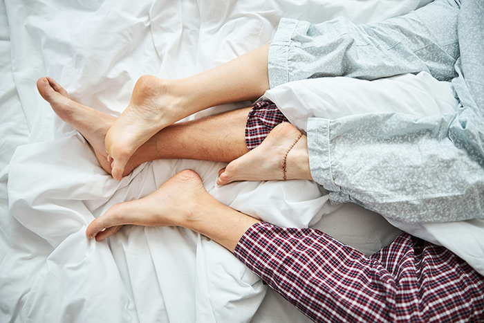 Couple's intertwined legs in bed representing cheating husband and relationship issues discussed by therapist.