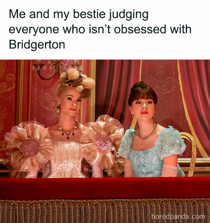 Two women in Bridgerton costumes sitting in a theater box, judging those not obsessed with Bridgerton series.