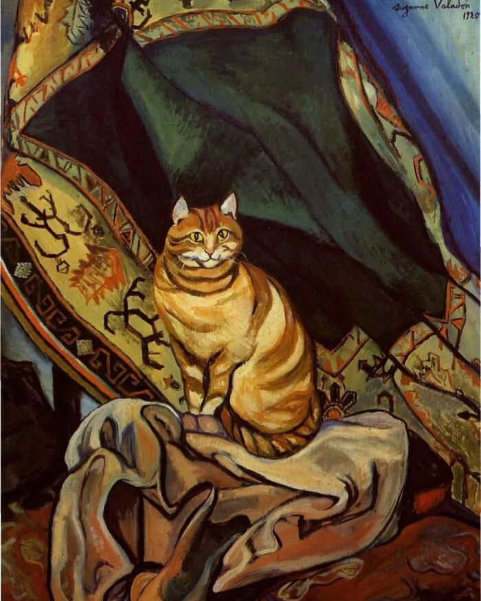 Painting of an orange tabby cat sitting on draped fabric with intricate patterns in a cat-themed artwork.