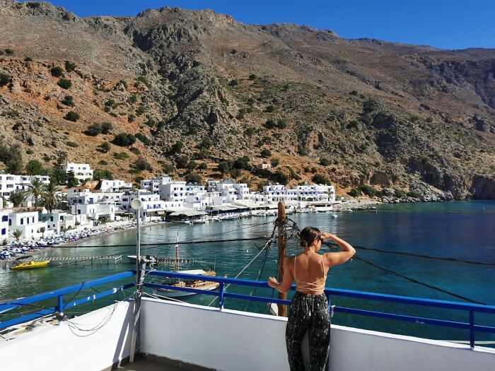 Woman overlooking seaside village from balcony, representing the experience of living out of a suitcase and questioning success. Woman overlooking seaside village from balcony, representing the experience of living out of a suitcase and questioning success.