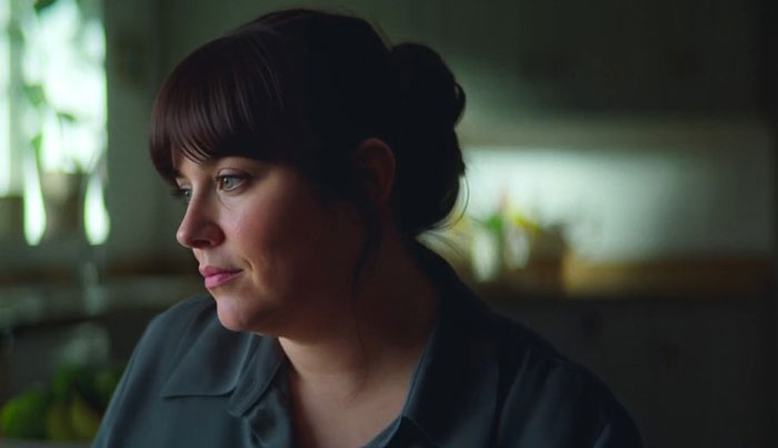 A woman with dark hair in a bun looking pensively to the side in a dimly lit room, reflecting Netflix Lucy Letby backlash.