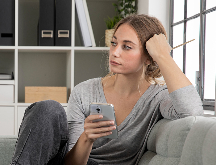 Woman looking tired and frustrated while holding a phone, reflecting fatigue from friend&rsquo;s strict diet enforcement.