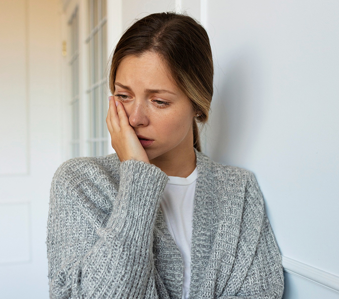 Woman wearing gray cardigan looking upset and thoughtful, reflecting on cheating husband and fair therapist issues.