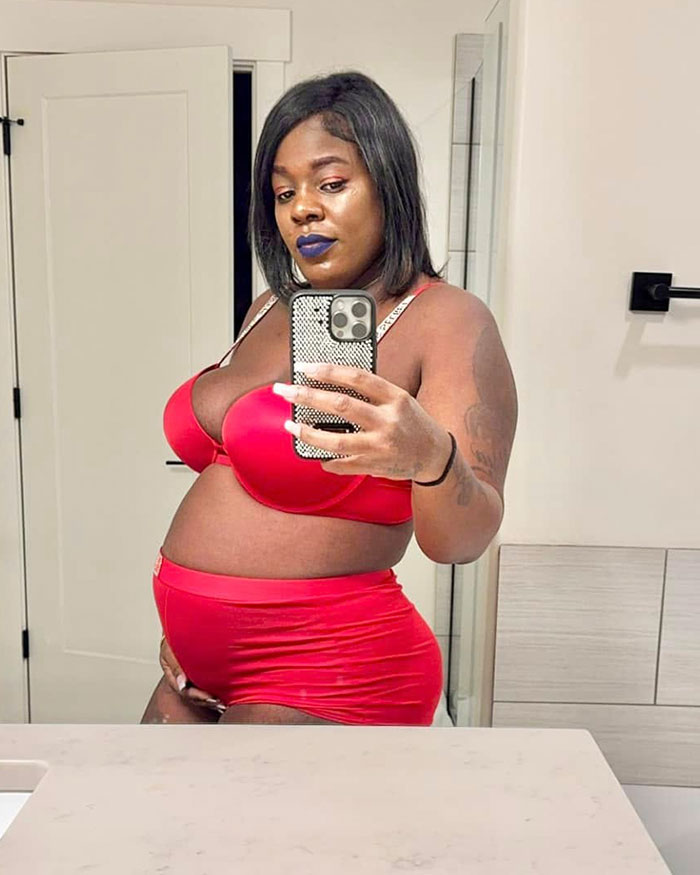 Pregnant woman taking a mirror selfie in red lingerie, related to surrogate suing couple after giving baby to them.