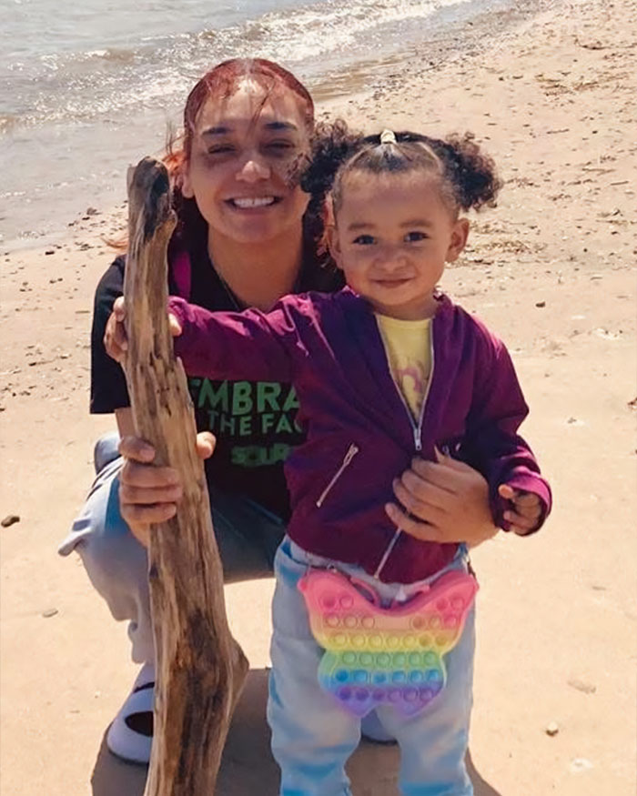 Young woman and child smiling on beach, related to missing woman located after family hears pleading call.