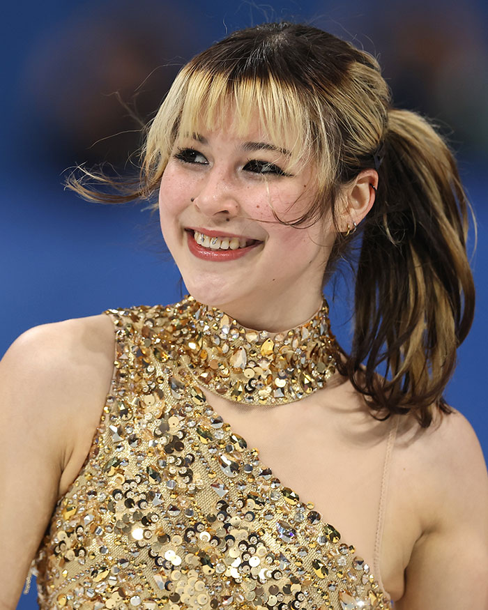 Figure skater Alysa Liu smiling during performance, with health experts warning fans eager to copy viral look.
