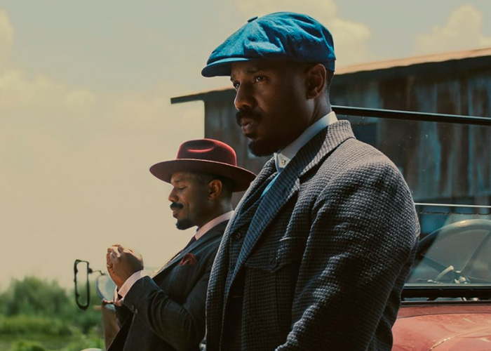 Michael B. Jordan in period costume with a hat, portraying twins in the Sinners role with notable facial appearance changes.