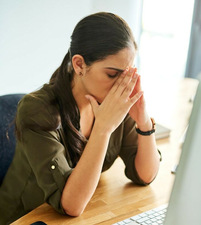 Stressed woman at desk with computer showing signs of toxic workplace moments and employee frustration.