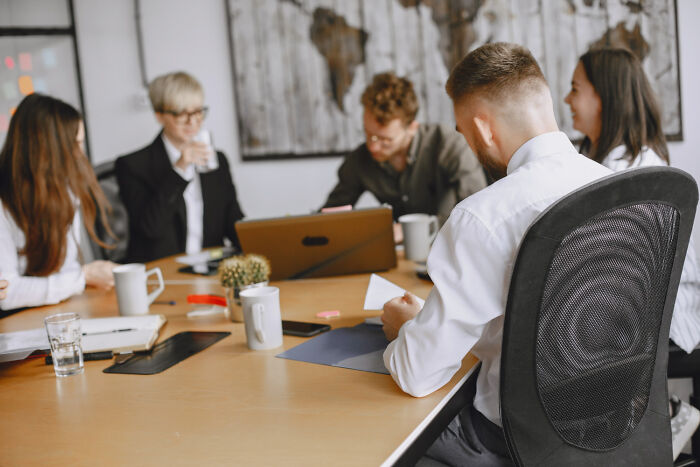 Group of professionals in a meeting room, engaged in discussion, illustrating brutal wake-up calls in tough situations.