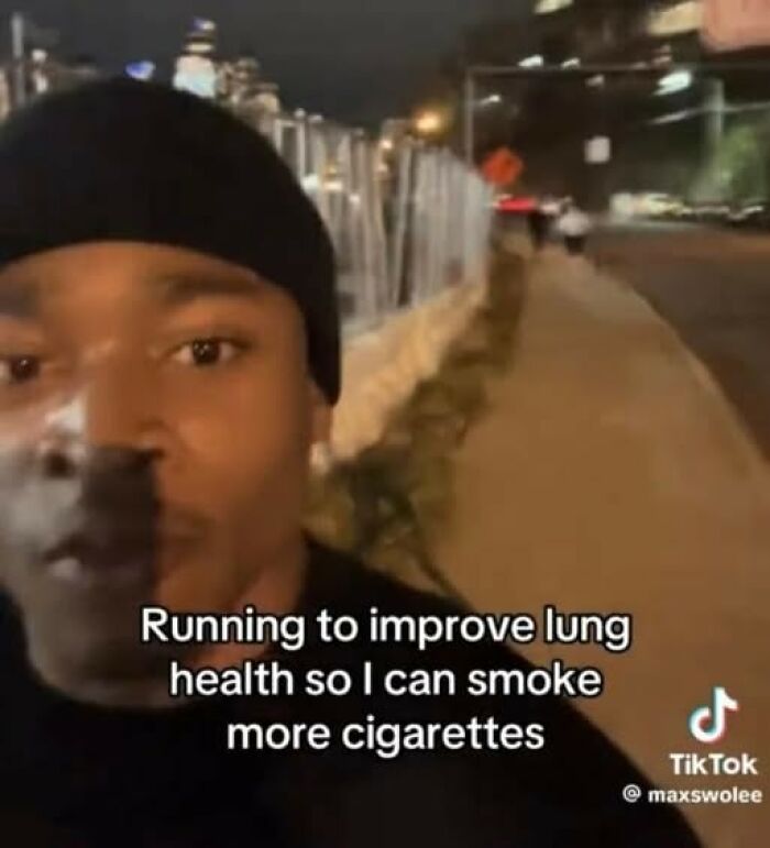 Man in a beanie outdoors at night with a cynical meme about running to improve lung health for smoking cigarettes.